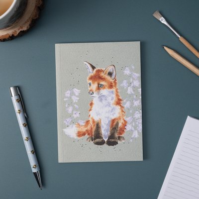 Fox illustration on A6 paperback notebook on a desk surrounded by a pen and pencil
