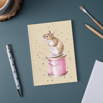 Mouse and Thread illustration on A6 paperback Notebook on a desk surrounded by pen and pencil 